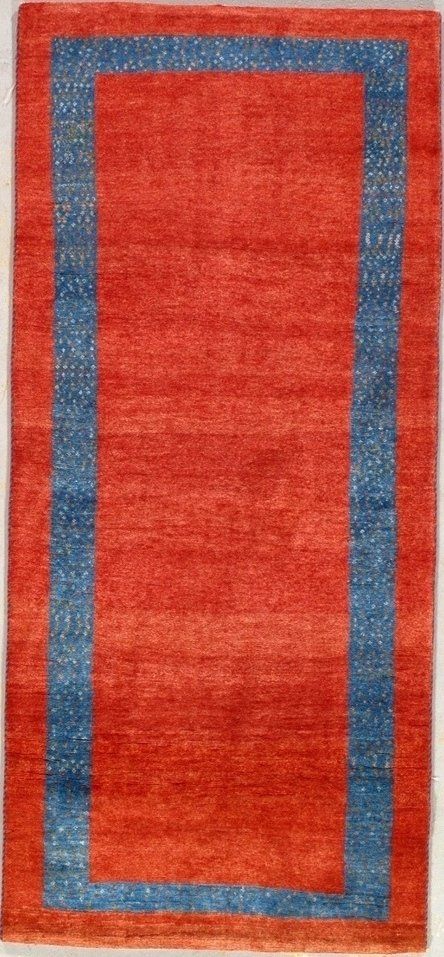 A red rug with a blue border is sitting on a white surface.