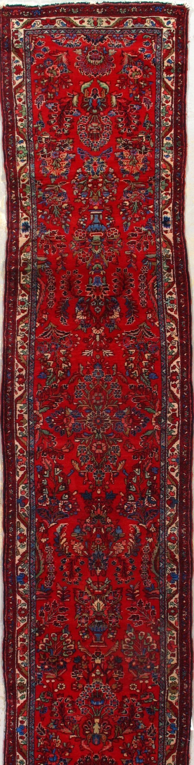 A red rug with a pattern on it is on a white surface.