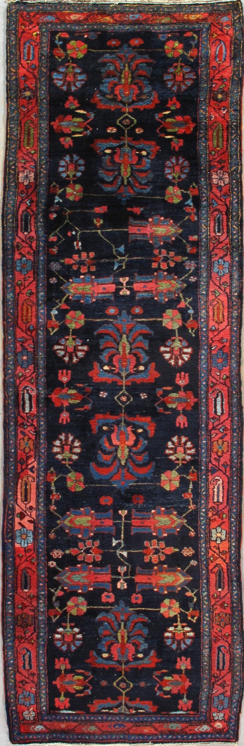 A rug with a floral pattern on it is hanging on a wall.