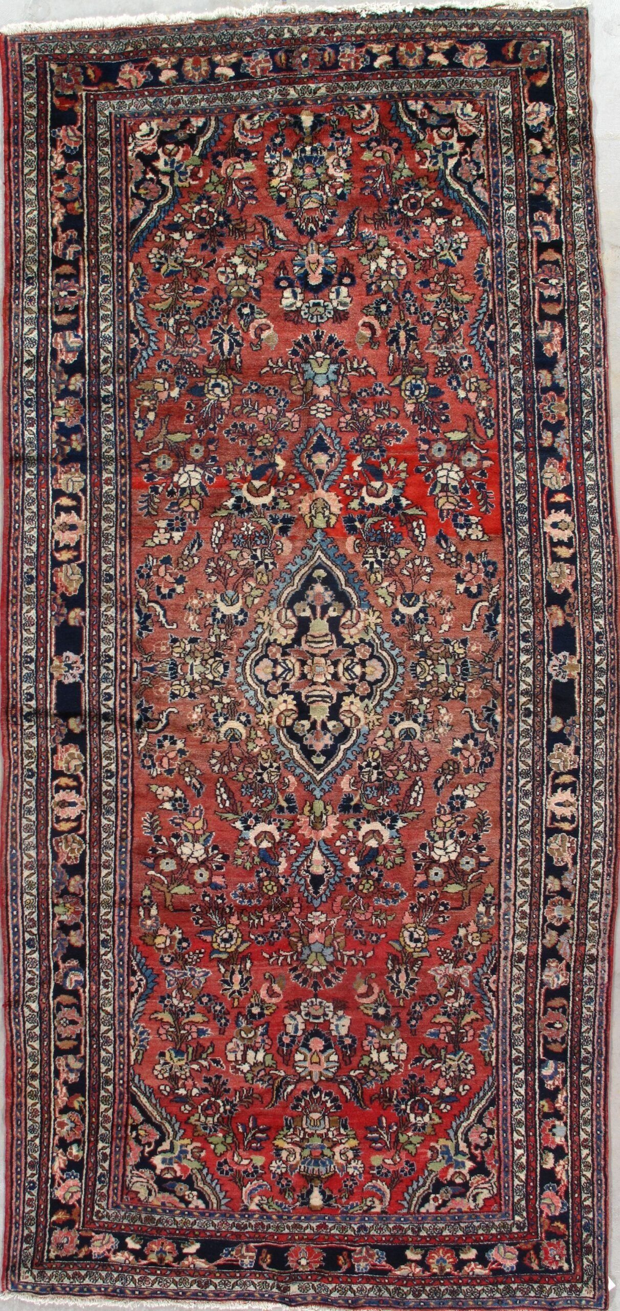 A red rug with a floral pattern is sitting on a white surface.