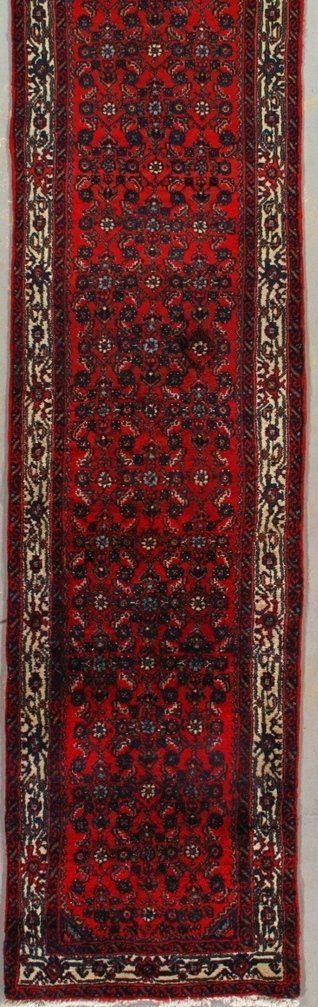 A red rug with a pattern on it is hanging on a wall.