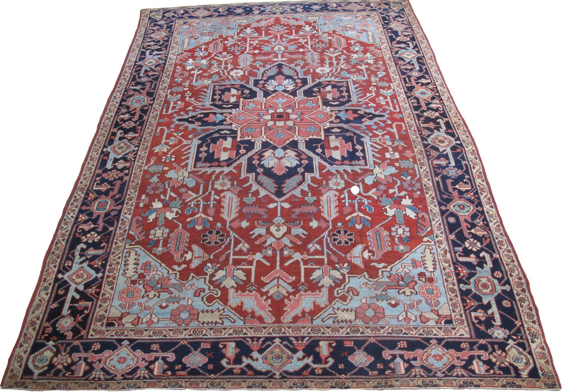 A red and blue rug with a floral pattern on a white background.