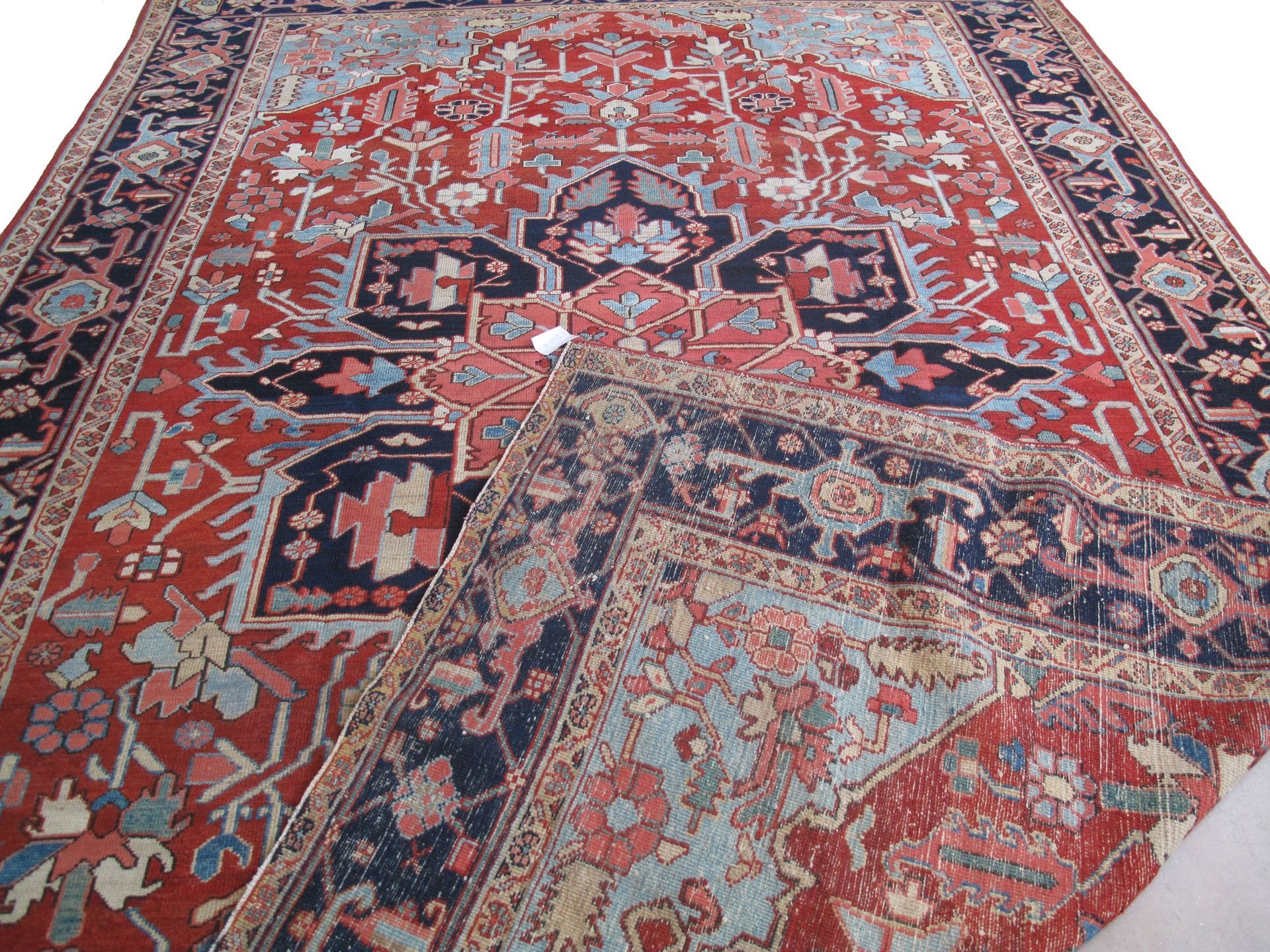 A red and blue rug with a floral pattern on a white background.