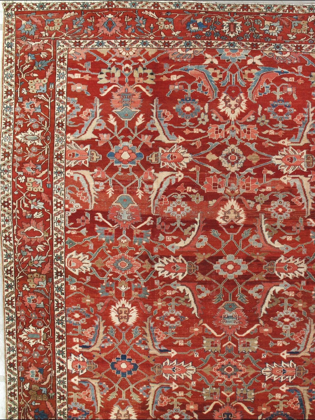 A red rug with a floral pattern is hanging on a wall.