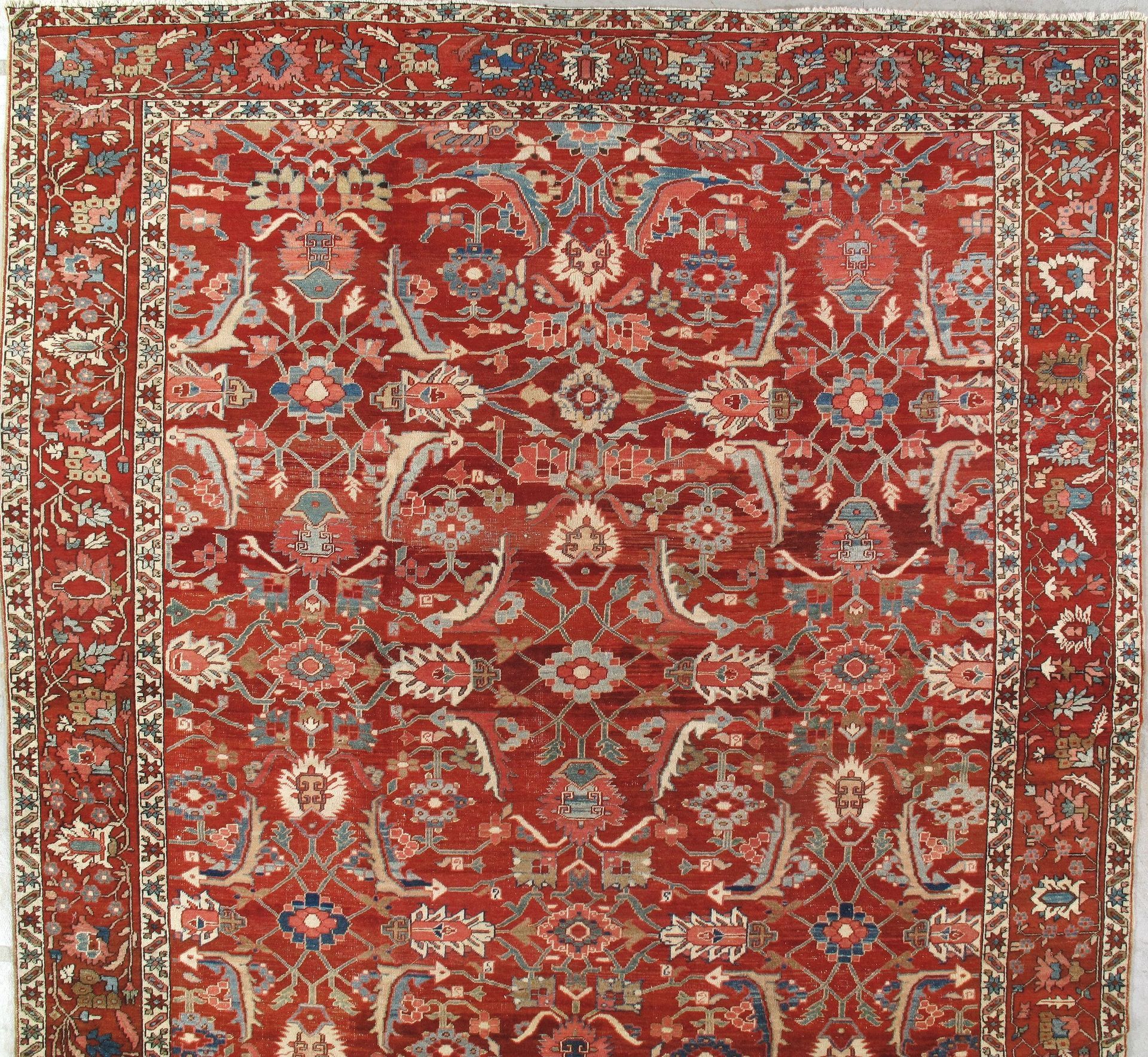 A red rug with a floral pattern is hanging on a wall.