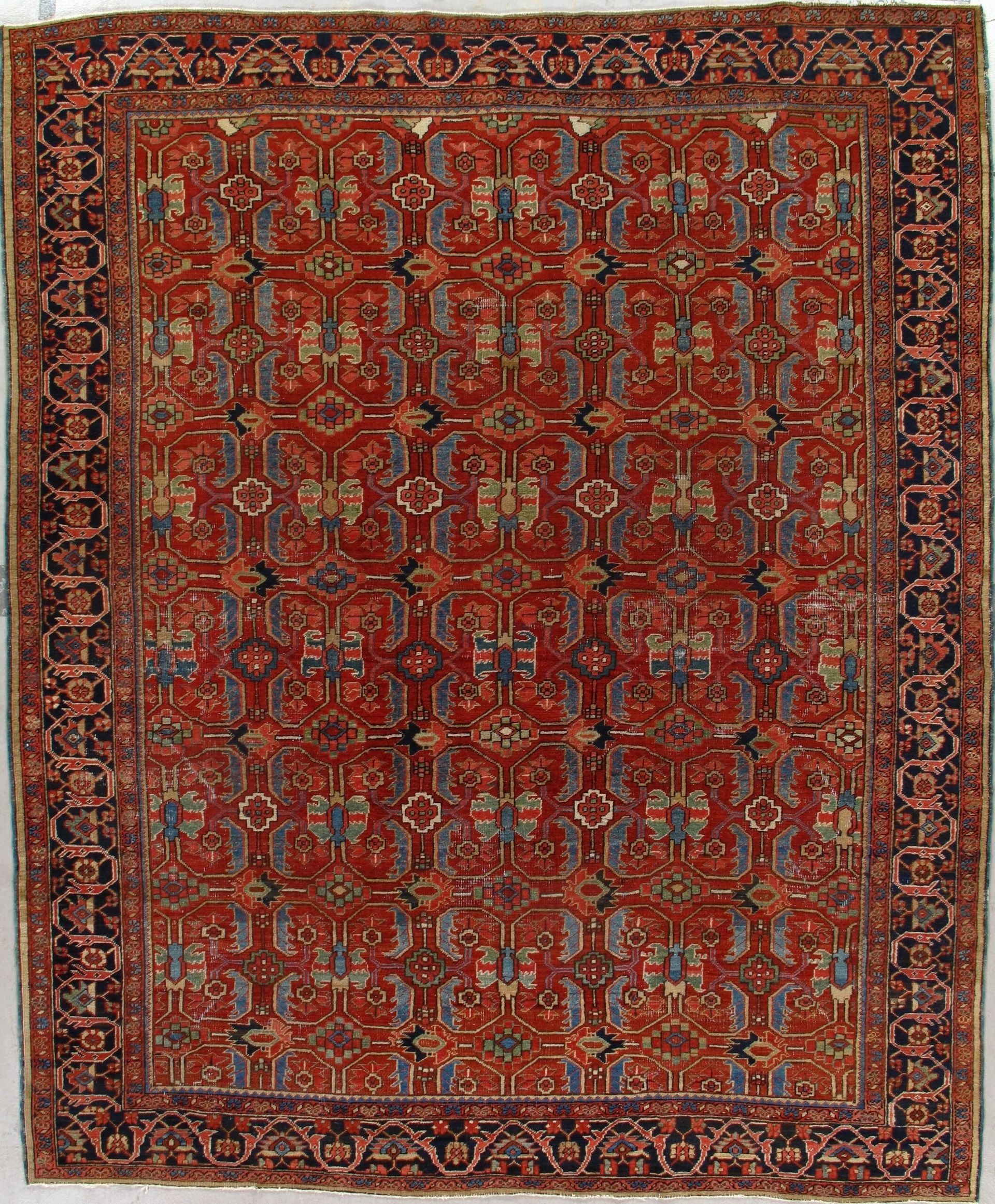 A red rug with a blue border is hanging on a white wall.