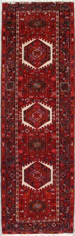 A red rug with white geometric designs on it is on a white background.