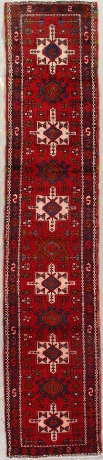 A red rug with a pattern on it is sitting on a white surface.