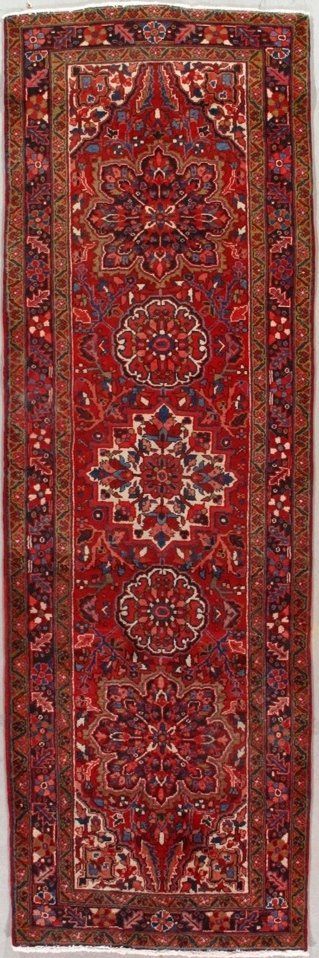 A red rug with a pattern on it is hanging on a wall.