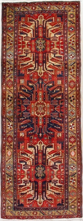 A red rug with a pattern on it is hanging on a wall.