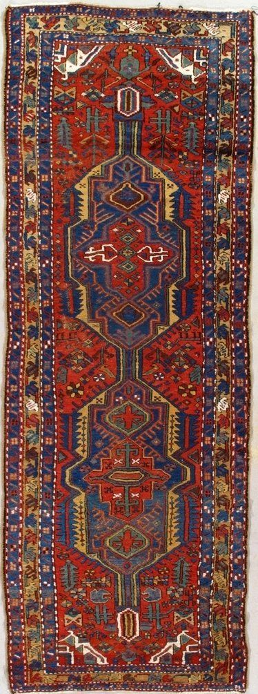 A red and blue rug with a pattern on it is hanging on a wall.