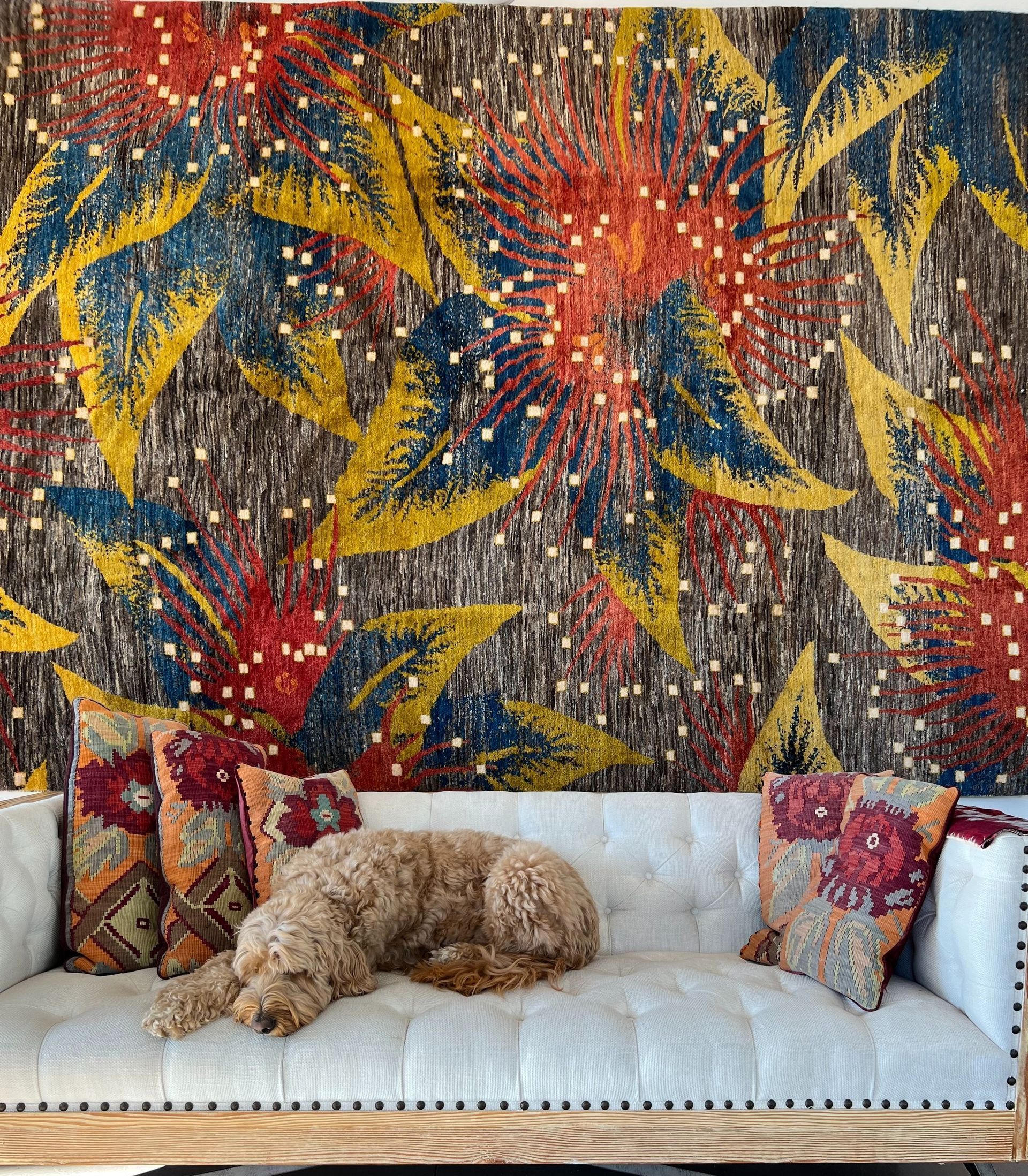 A dog is laying on a couch in front of a colorful wall mural.