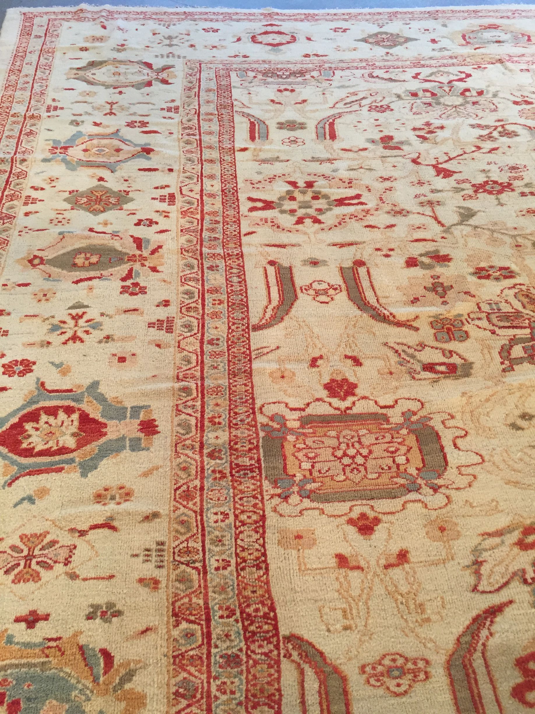 Beige and red oriental rug on wooden floor.