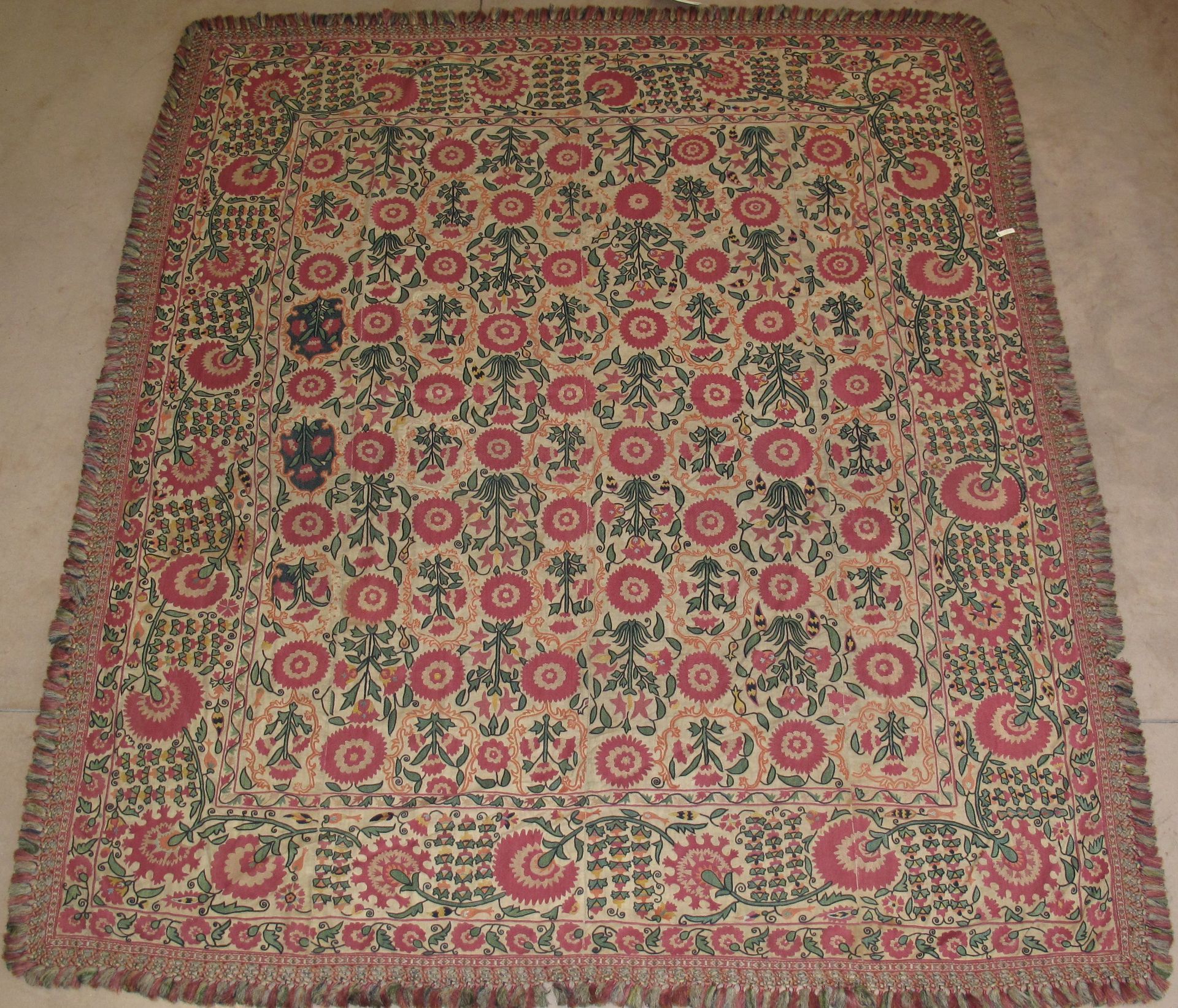 Square textile with red floral pattern and fringed border.