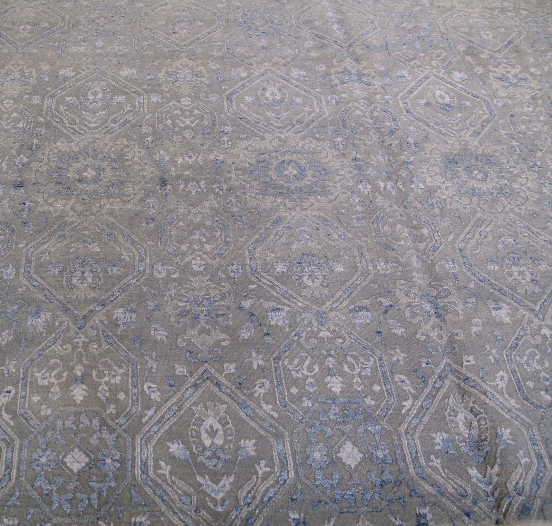 A gray rug with a pattern on it is sitting on a white surface.