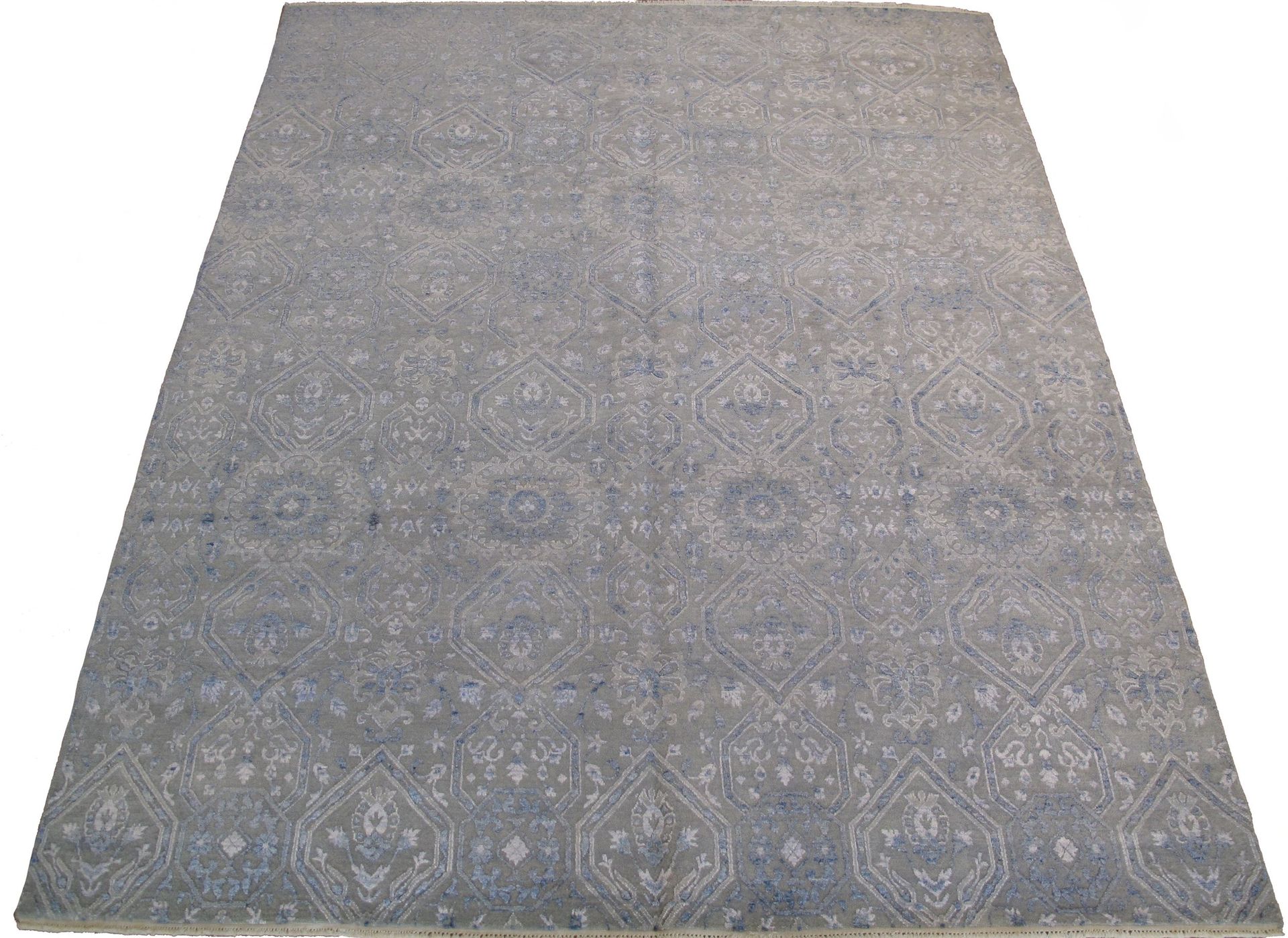 A gray rug with a pattern on it is sitting on a white surface.