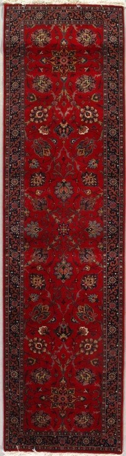 A red rug with a pattern on it is hanging on a wall.