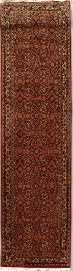 A red rug with a pattern on it is hanging on a wall.