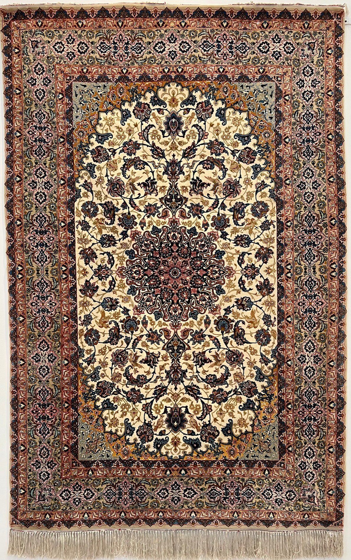 A rug with a floral pattern on it is hanging on a wall.