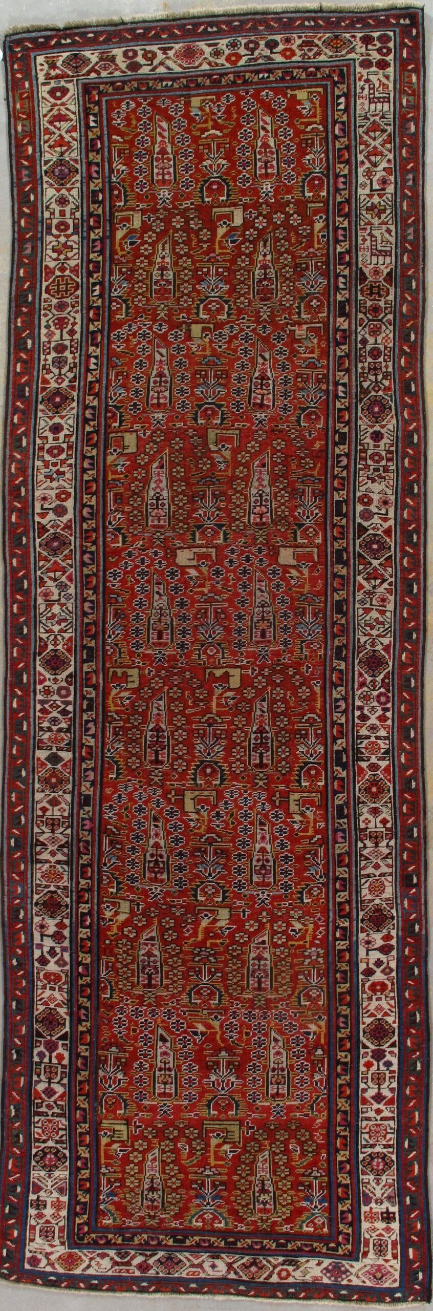 A red rug with a pattern on it is hanging on a wall.