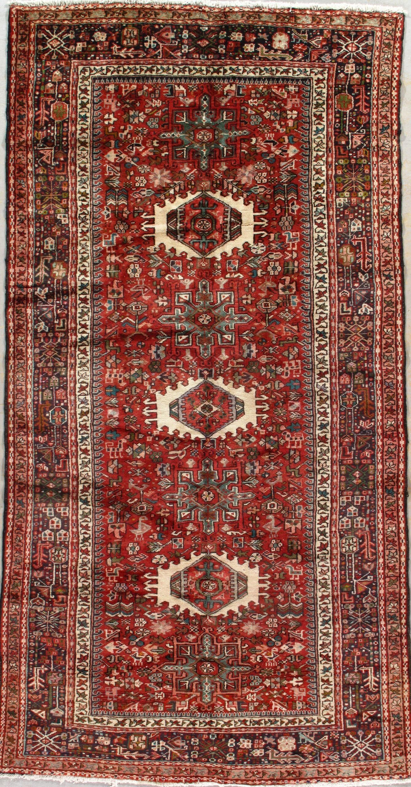 A red rug with a pattern on it is sitting on a white surface.