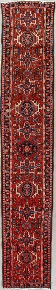 A red rug with a pattern on it is hanging on a wall.