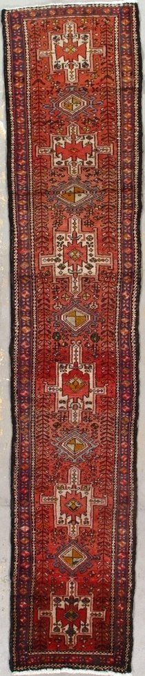 A red rug with a pattern on it is hanging on a wall.