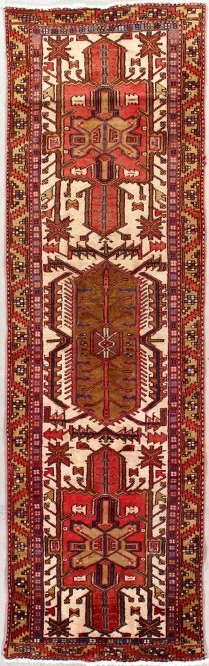 A red rug with a pattern on it is hanging on a wall.