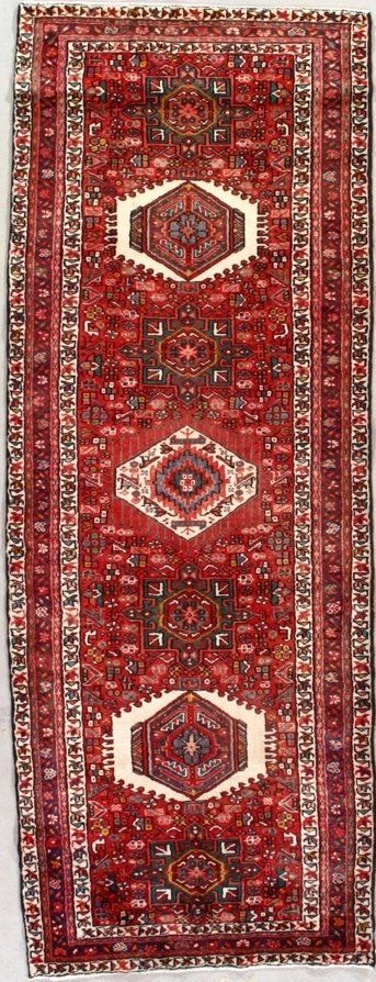 A red rug with a pattern on it is sitting on a white surface.