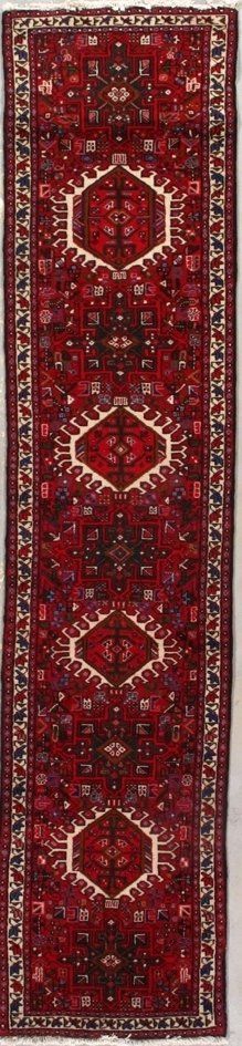 A red rug with a pattern on it is hanging on a wall.