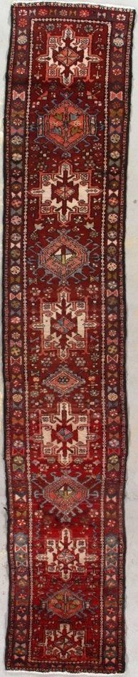 A red rug with a pattern on it is sitting on a white surface.