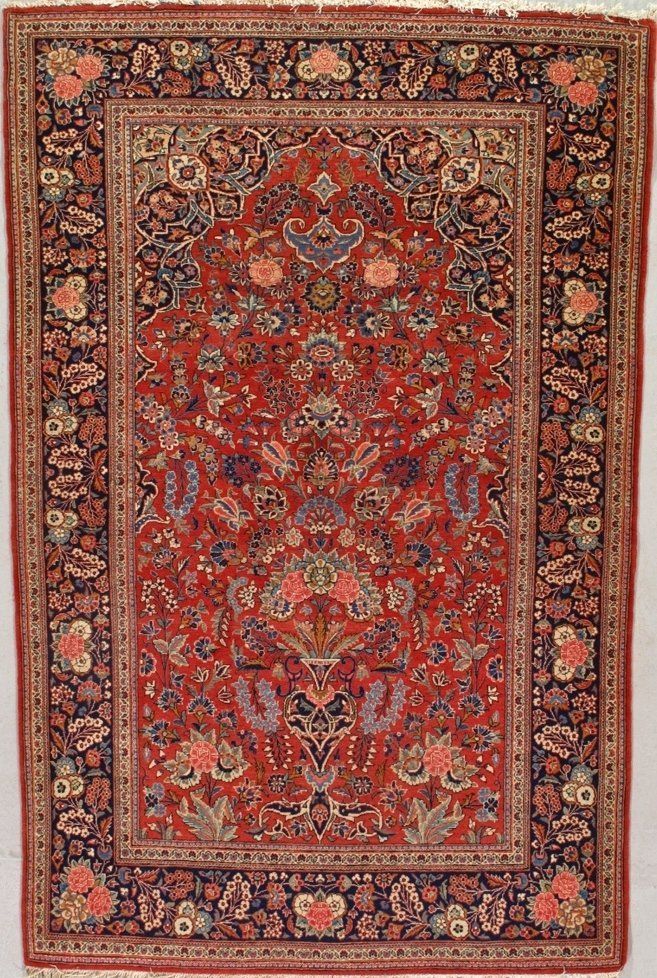 A red rug with a floral pattern is hanging on a wall.