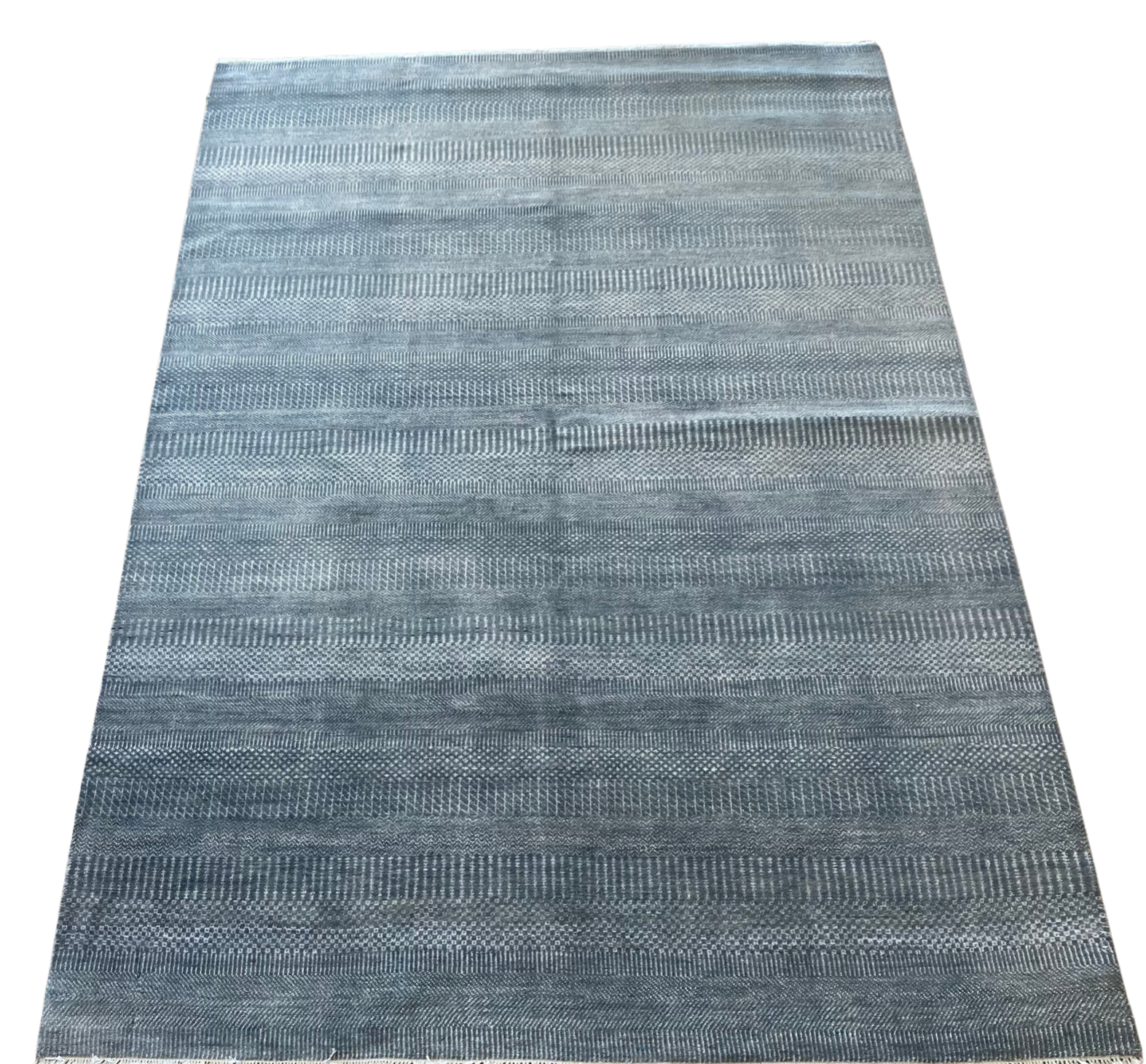 A blue rug with a pattern on it is on a white background.