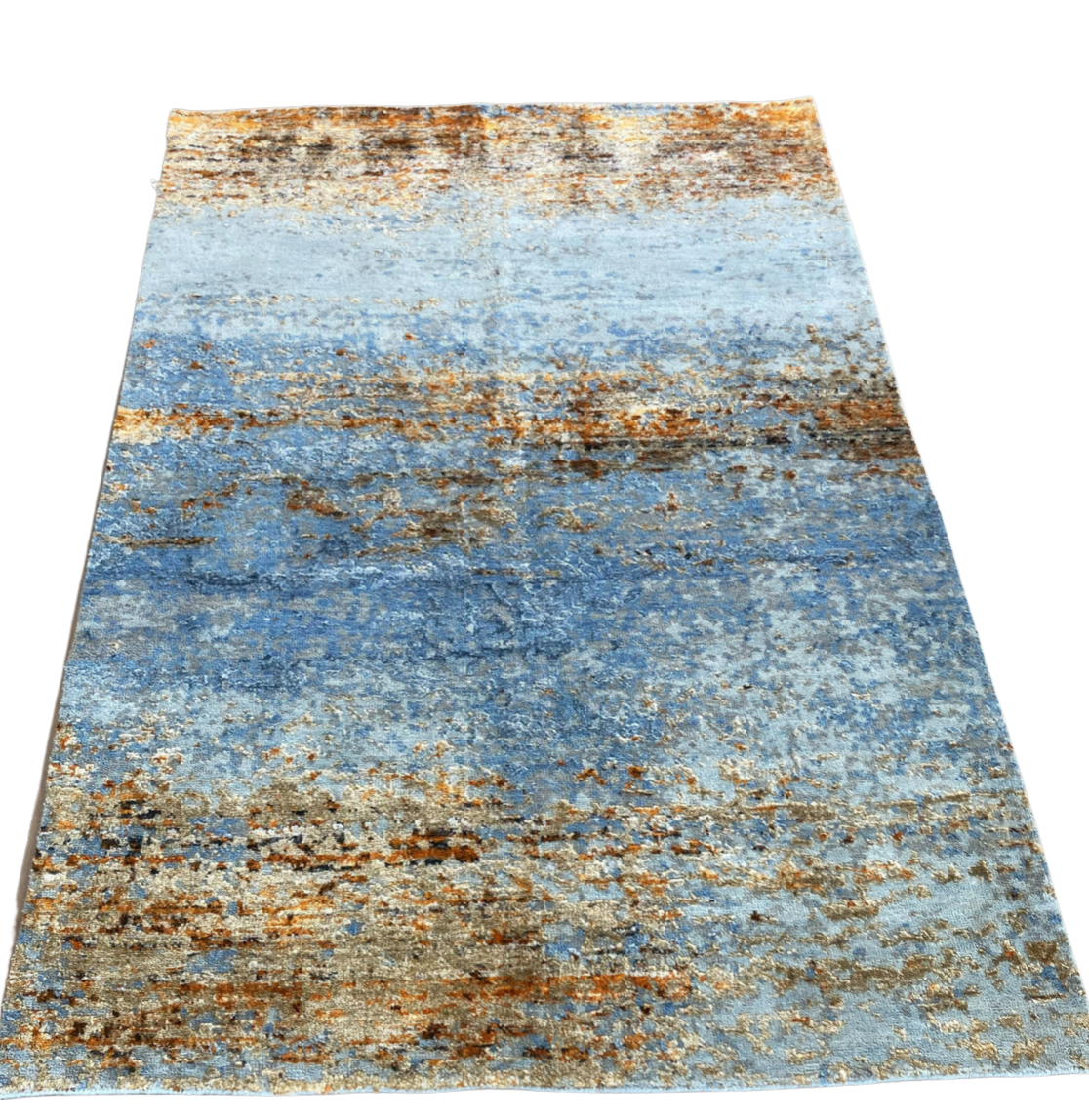 A blue and brown rug is sitting on a white surface.