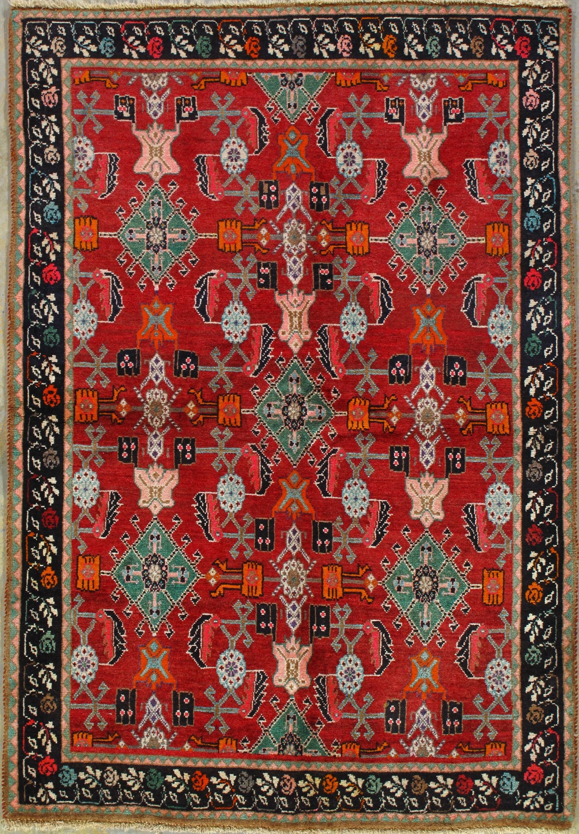 A red rug with a floral pattern on it is hanging on a wall.