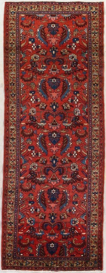 A red rug with a floral pattern on it is sitting on a white surface.