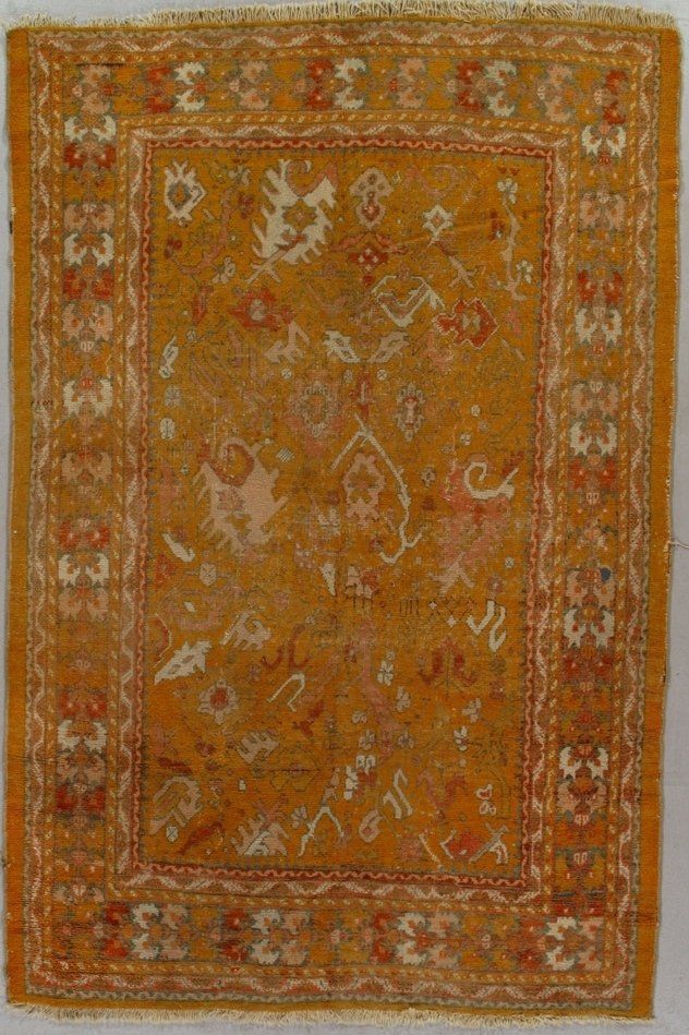 A yellow rug with a floral pattern on it is on a white surface.