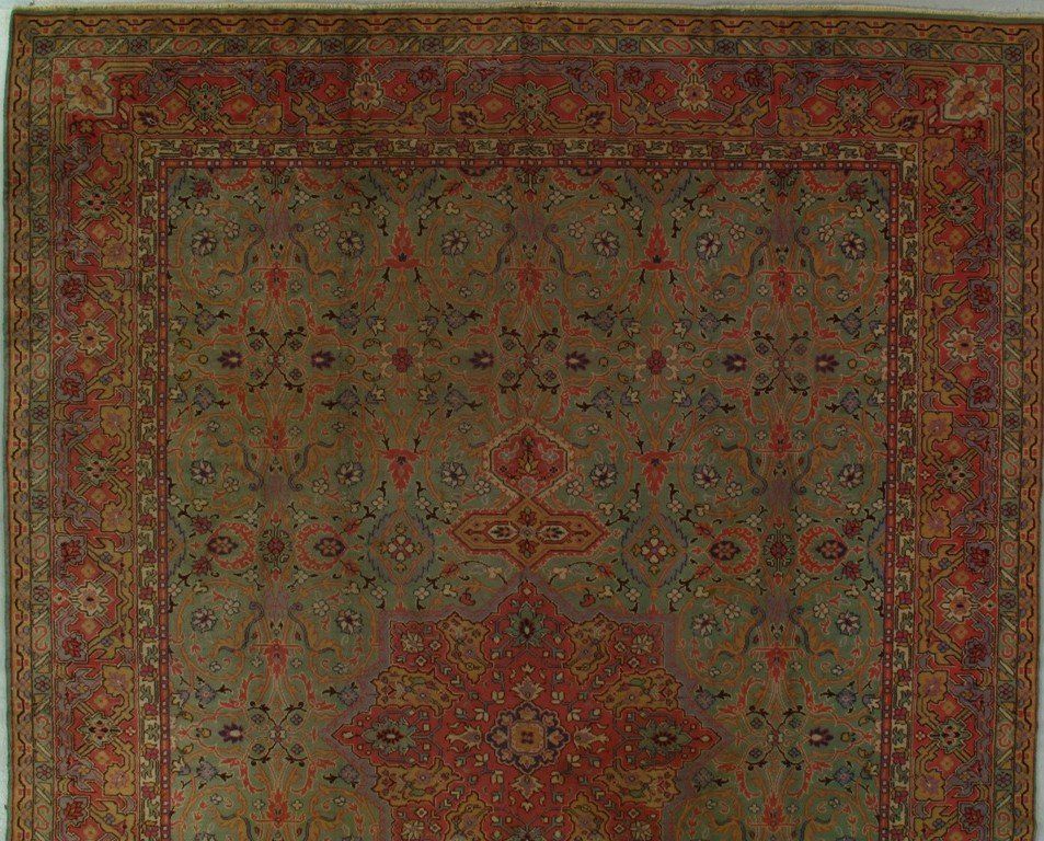 A rug with a floral pattern on it is hanging on a wall.