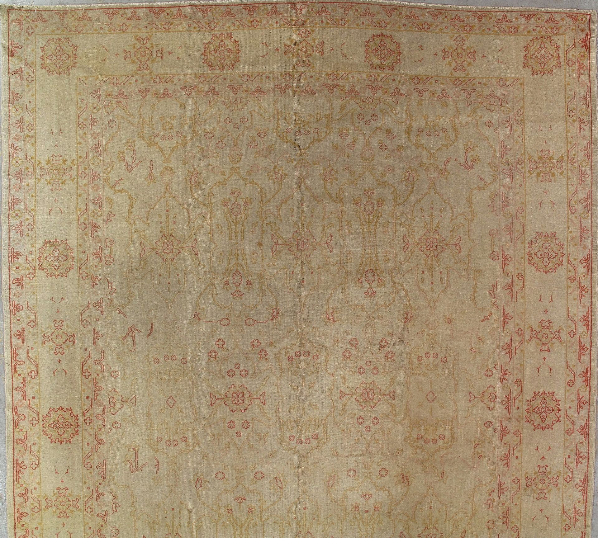 A beige and red rug with a floral pattern on it