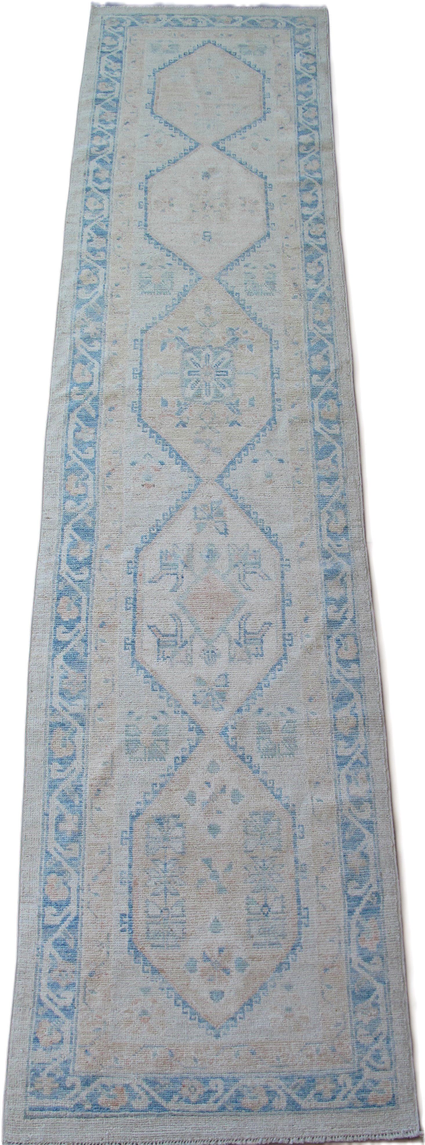 A blue and white rug with a pattern on it is on a white background.