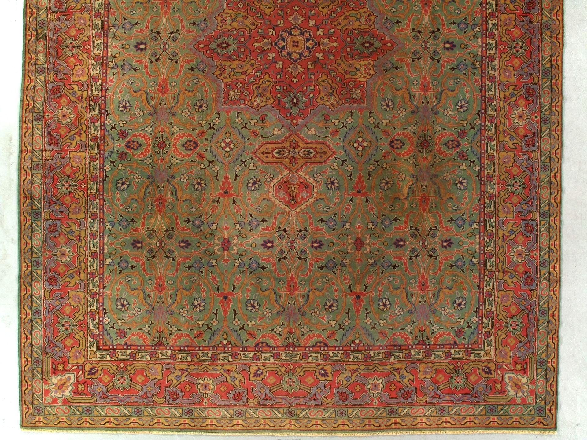 A rug with a floral pattern on it is hanging on a wall.