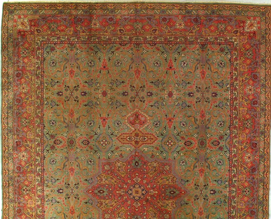 A rug with a floral pattern on it is hanging on a wall.