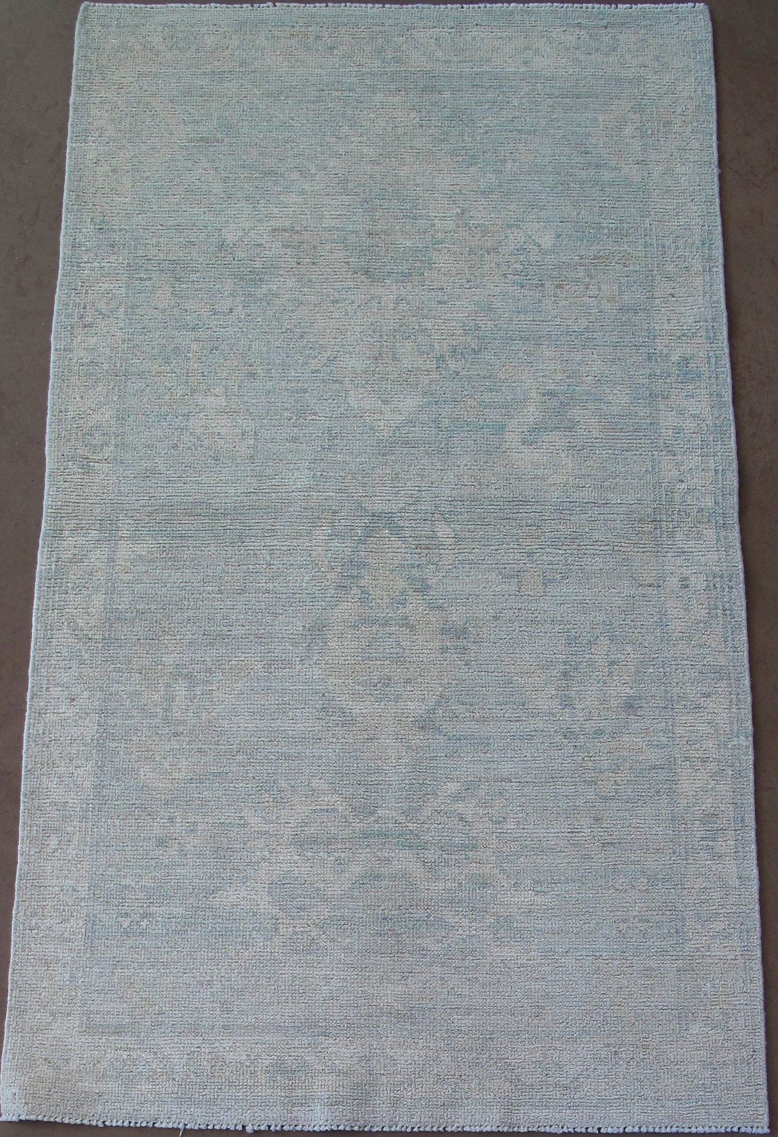 A gray rug is sitting on a brown surface