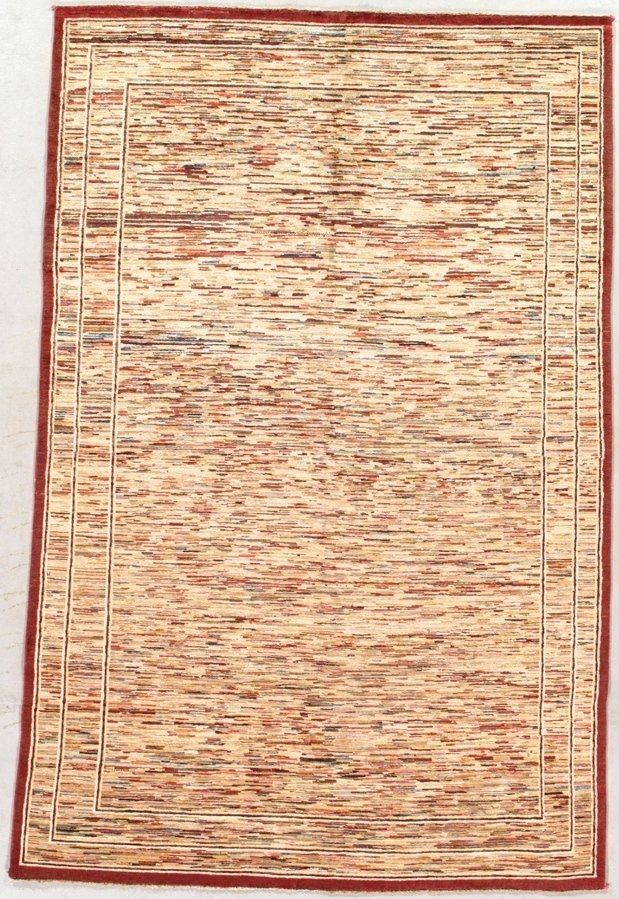 A rug with a red border is sitting on a white surface.