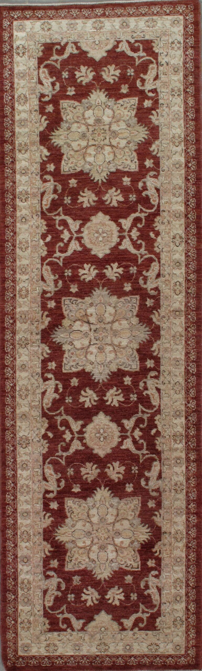 A red and white rug with a pattern on it is hanging on a wall.