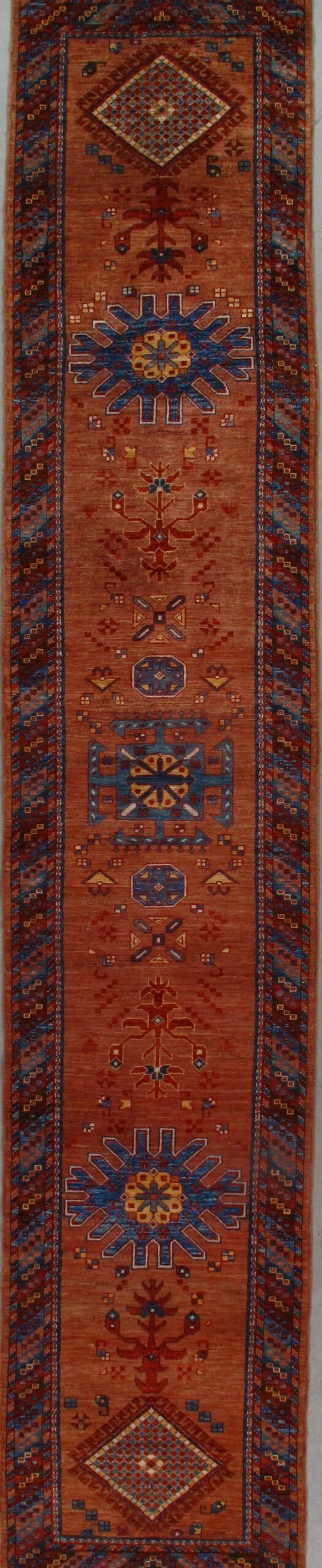 A red rug with a blue and yellow pattern is hanging on a wall.