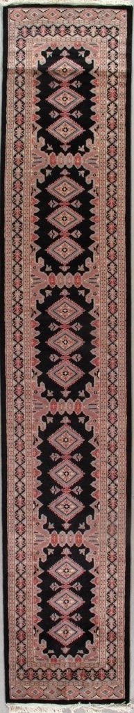 A rug with a geometric pattern on it is hanging on a wall.
