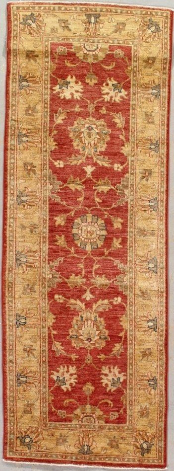 A red and yellow rug with a floral pattern is hanging on a wall.
