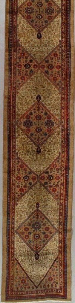 A long rug with a pattern on it is hanging on a wall.