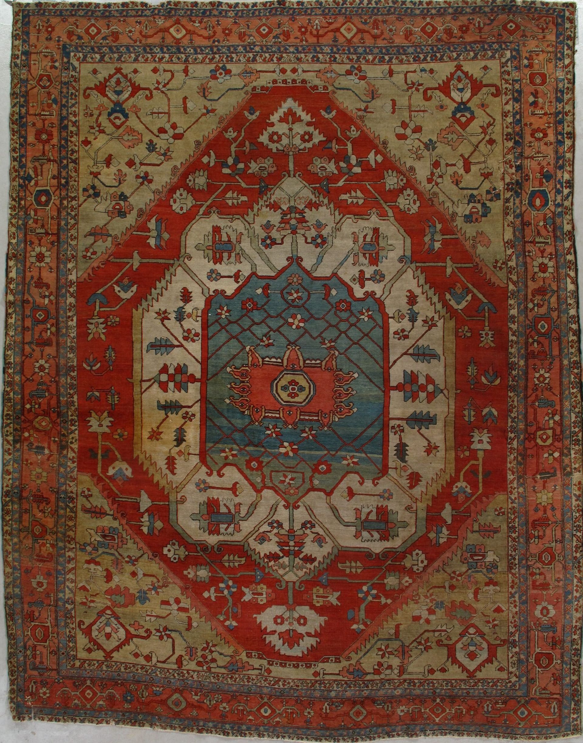 A rug is hanging on a white wall and has a floral pattern on it.